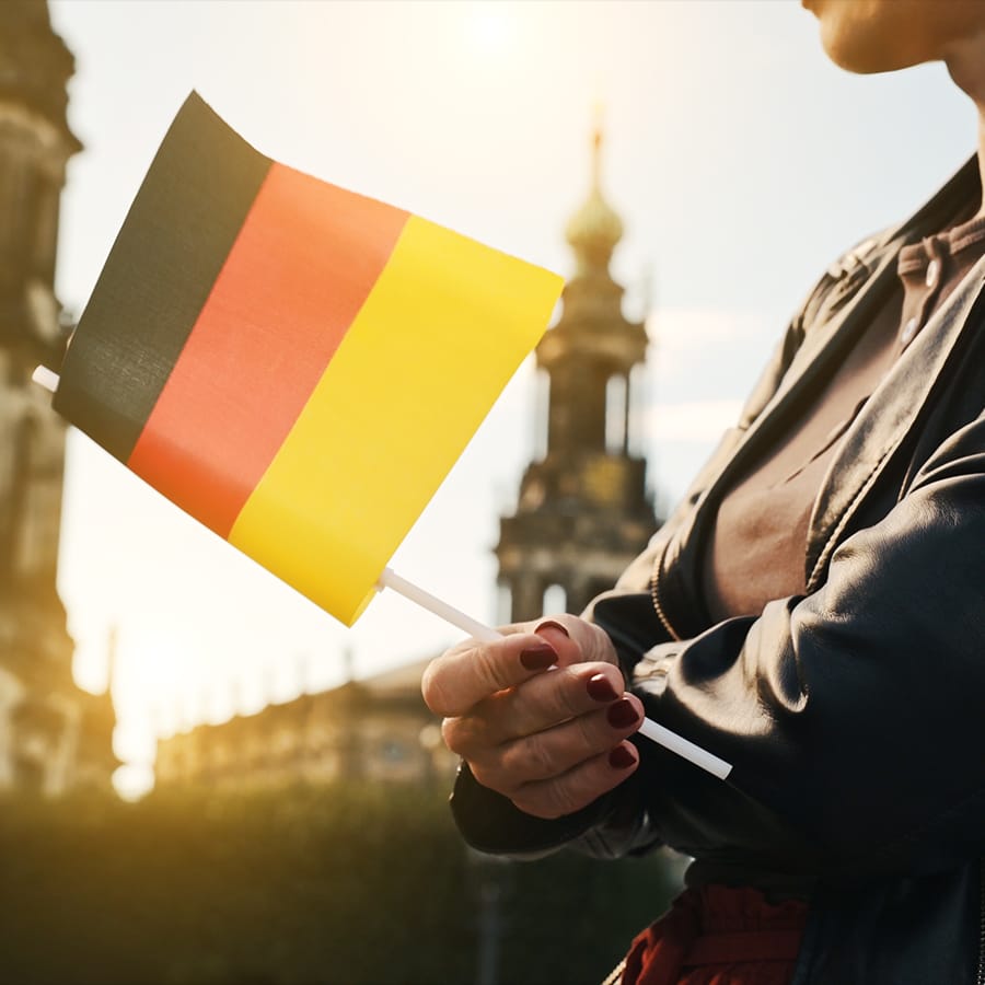 Eine Frau schwenkt eine deutsche Fahne vor einem historischen Gebäude.